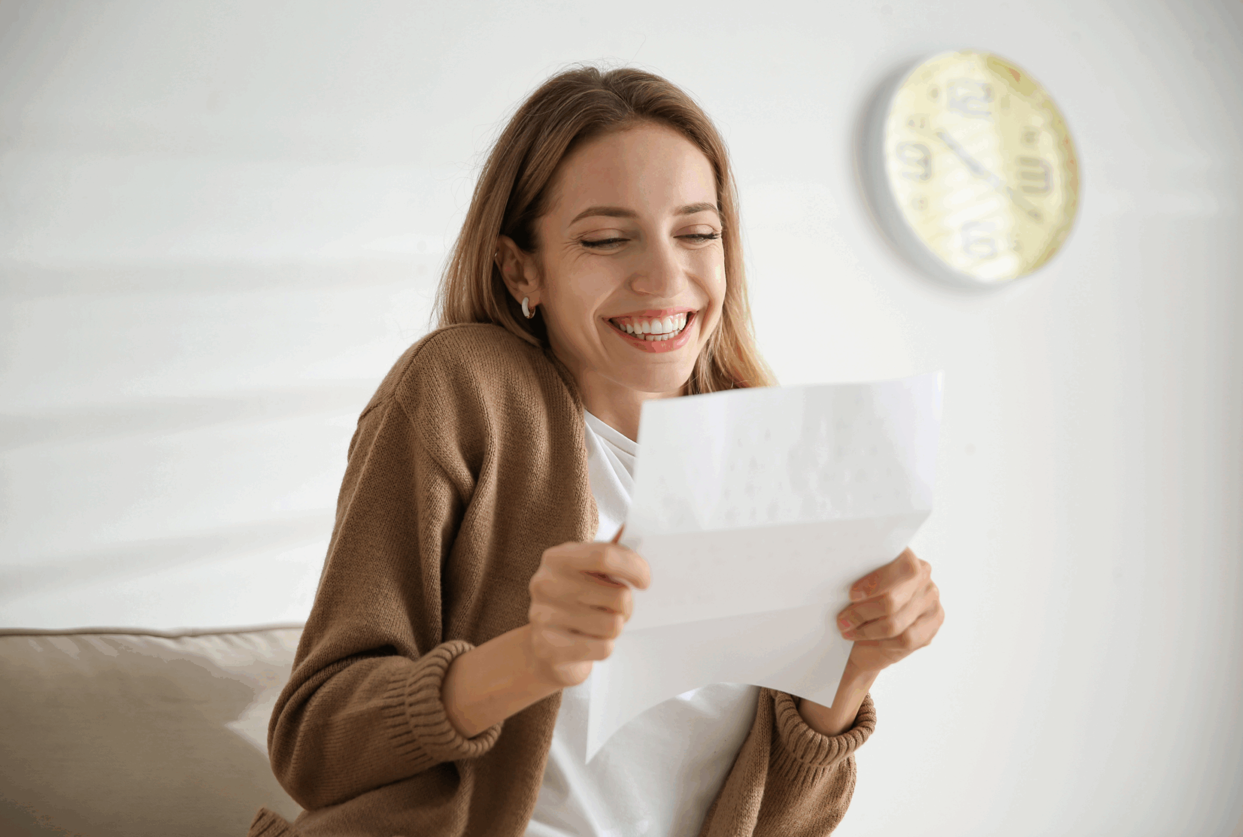 woman opening up letter with a smile on her face